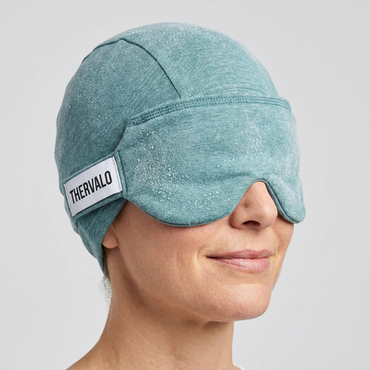 Woman wearing the Thervalo cooling relief cap with the eye-mask panel pulled down